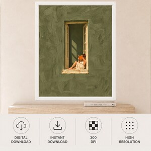 May include: A framed wall art print featuring a textured olive green wall with a central open window. A figure in a light-colored dress sits in the window frame reading an orange book, with sunlight casting shadows across the interior space.