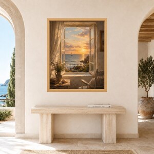 May include: A framed wall art print depicting an open window view of a sunset over the ocean with a sailboat, a wooden chair, and a small table with a vase of flowers and books, displayed above a long, rectangular, light-colored stone console table.