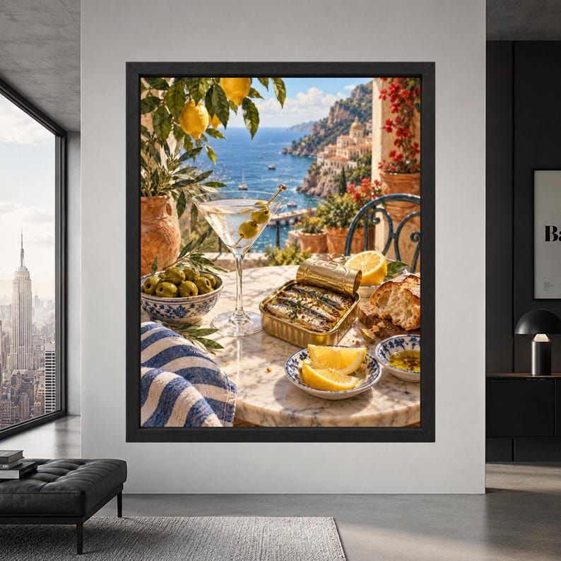 Framed Mediterranean kitchen wall art showing an open tin of sardines, martini with olives, lemons, bread and green olives on a marble table overlooking the blue sea and Amalfi Coast.