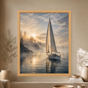 Framed sailboat wall art showing a white sailing yacht on calm water at sunrise with a lighthouse, pine-covered shoreline, soft coastal fog and warm golden reflections.