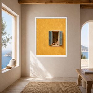 Puede incluir: Una l&aacute;mina de arte enmarcada que muestra una pared de color amarillo mostaza con textura y una ventana abierta. La ventana tiene contraventanas de color azul claro y muestra a una persona sentada en el alf&eacute;izar leyendo un libro.