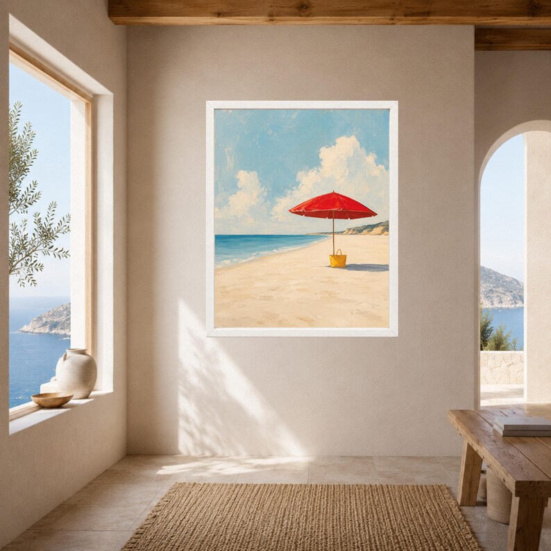 May include: A framed wall art print depicting a beach scene with a bright red umbrella standing on the sand next to a yellow bag. The painting features a clear blue sky with white clouds, a calm ocean, and a sandy shoreline in a white frame.