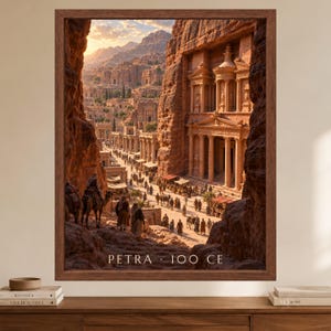 May include: A framed wall art print depicting the ancient city of Petra with sandstone cliffs, a carved temple facade, and people with camels on a path. The text PETRA 100 CE is printed at the bottom of the image within a dark brown wooden frame.