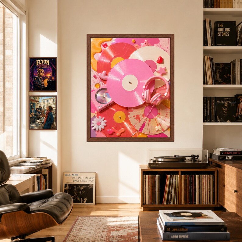May include: A framed wall art print featuring a collage of pink, red, and white vinyl records, a pair of pink headphones, and small decorative elements like stars and flowers, displayed in a room with a record player and bookshelves.