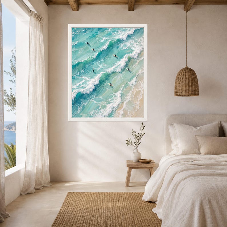 May include: A framed wall art print featuring an aerial view of turquoise ocean waves crashing onto a sandy beach. Several small figures on surfboards are positioned within the rolling white-capped water, captured in a textured, painterly style.