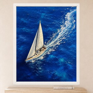 May include: A framed wall art print featuring an aerial view of a white sailboat navigating through deep blue ocean waters. The vessel leaves a prominent white wake behind it, contrasting with the vibrant, textured shades of the sea surface.