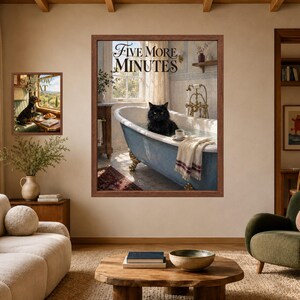 May include: Two framed wall art prints in a room. The larger print shows a black cat in a blue clawfoot bathtub with the text "FIVE MORE MINUTES" and a coffee cup. The smaller print shows a dog on a train seat with the text "WINDOW SEAT".