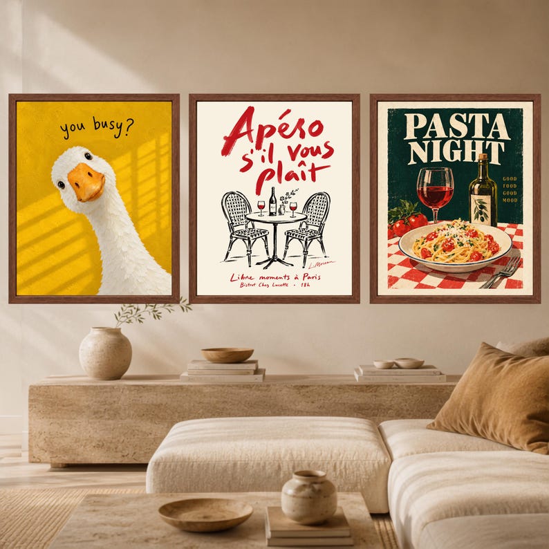 May include: A set of three framed wall art prints. The left print features a white goose on a yellow background with the text you busy?. The middle print shows a bistro table with chairs and the text Ap&eacute;ro s'il vous pla&icirc;t. The right print shows pasta.