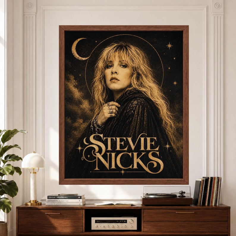 Framed Stevie Nicks wall art featuring a vintage-inspired rock portrait in black and gold with flowing blonde hair, crescent moon, celestial stars and large ornate “Stevie Nicks” typography above a record player console.