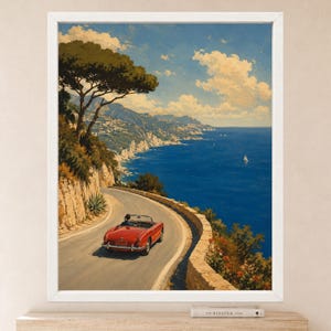 May include: A framed wall art print depicting a red convertible driving along a winding coastal road. The scene features a deep blue sea, rocky cliffs, a large pine tree, and a clear sky with white clouds. A small sailboat is visible on the water.