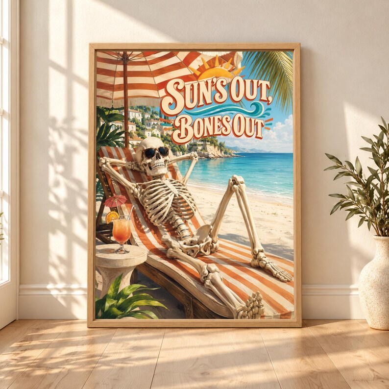 Framed Sun’s Out Bones Out skeleton wall art showing a skeleton in sunglasses relaxing on a striped beach lounger beside a tropical drink overlooking a bright turquoise coast.
