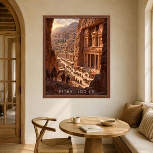 May include: A framed wall art print depicting the ancient city of Petra with its carved stone architecture, columns, and figures with camels in a desert landscape. The text PETRA 100 CE is printed in white at the bottom of the image.