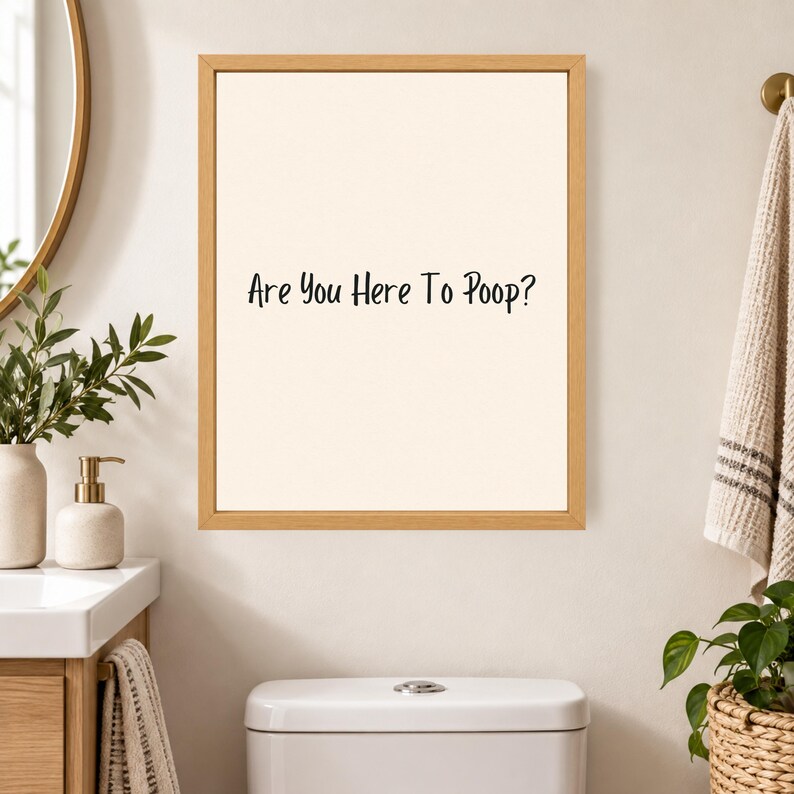 May include: A rectangular wall art piece featuring a light beige background and a thin wooden frame. The text "Are You Here To Poop?" is printed in black, sans-serif lettering in the center of the print, creating a clear and legible display.