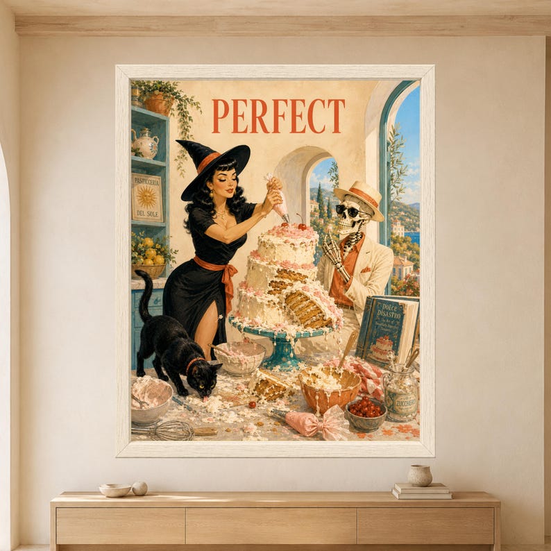 Framed Perfect wall art showing a retro witch decorating a collapsing pink layer cake beside a skeleton in a cream suit while a black cat walks across a messy Mediterranean bakery counter.