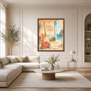 May include: A framed wall art print titled Coastal Chords featuring a coral-coloured electric guitar on a stand, connected by a cable to a small amplifier, set against a Mediterranean-style patio overlooking a bright blue sea and sky.