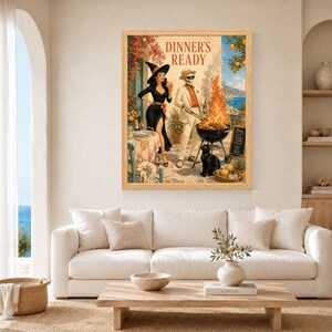 May include: A framed wall art print titled DINNER'S READY featuring a woman in a black dress and witch hat standing next to a skeleton in a white suit grilling food over a fire. A black cat sits nearby on a patio overlooking the ocean.