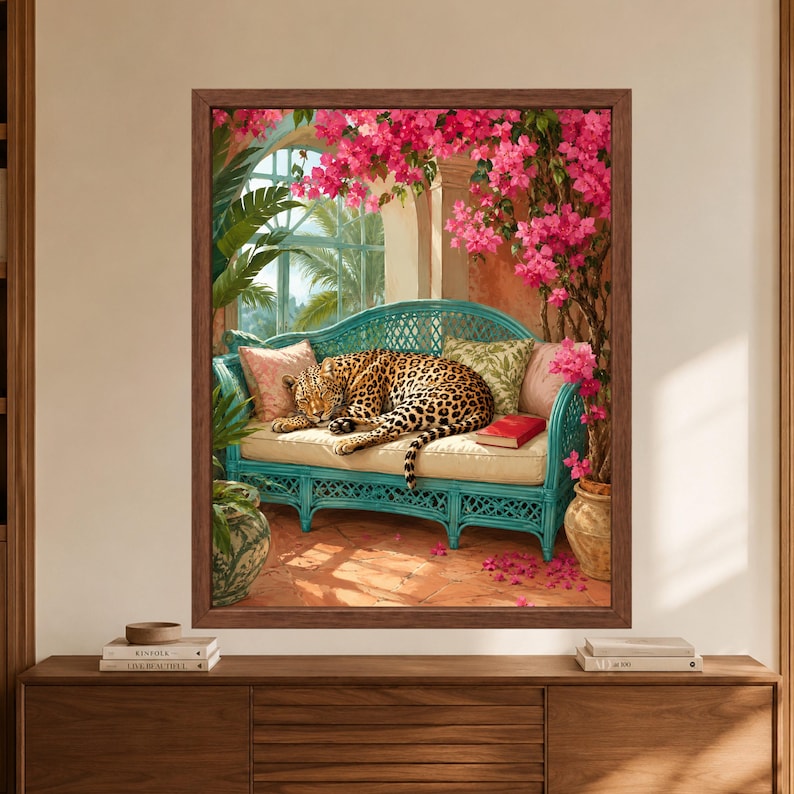 Framed tropical leopard wall art showing a sleeping leopard curled on a turquoise wicker sofa beneath vivid pink bougainvillea, surrounded by palms, patterned cushions and warm terracotta flooring.