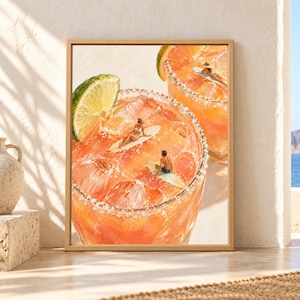 Framed cocktail wall art showing oversized coral margarita-style drinks with salted rims, ice and lime wedges while tiny surfers relax on surfboards floating inside the glasses.