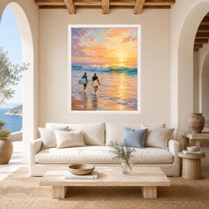 May include: A framed wall art print depicting two surfers walking into the ocean at sunset. The scene features golden and orange clouds, a breaking wave, and the surfers carrying surfboards. The artwork is displayed in a white frame.