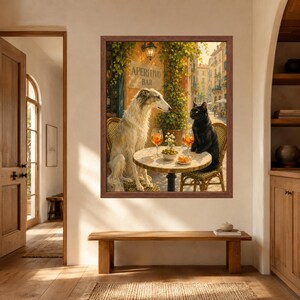May include: A framed wall art print depicting a white Borzoi dog and a black cat sitting at a round outdoor cafe table. The table holds two glasses of orange liquid, a small bowl of green olives, and a plate of snacks. A sign reads APERITIVO BAR.