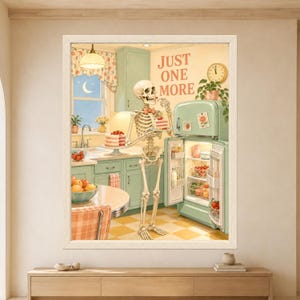 Framed Just One More skeleton wall art featuring a bow-tie skeleton eating strawberry cake beside an open mint green refrigerator in a pastel retro kitchen at night.
