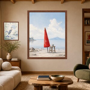 May include: A large framed wall art print featuring a vibrant red Japanese paper umbrella standing on a sandy beach near a wooden stool, with a calm sea and distant mountains under a blue sky. A smaller framed print of a heron is also displayed.