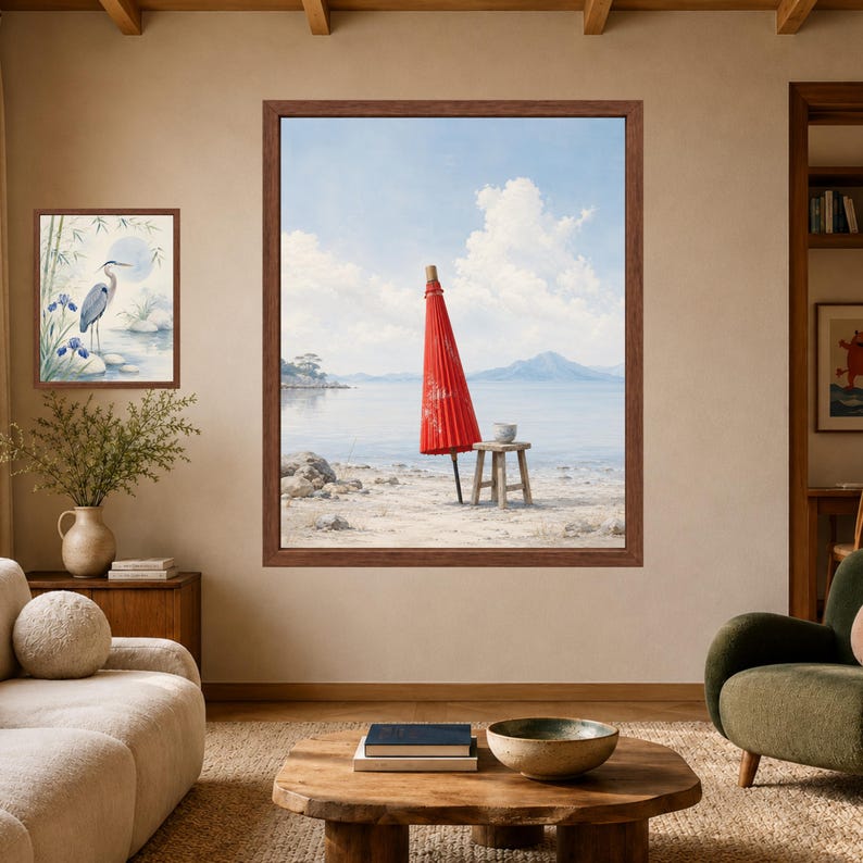 May include: A large framed wall art print featuring a vibrant red Japanese paper umbrella standing on a sandy beach near a wooden stool, with a calm sea and distant mountains under a blue sky. A smaller framed print of a heron is also displayed.