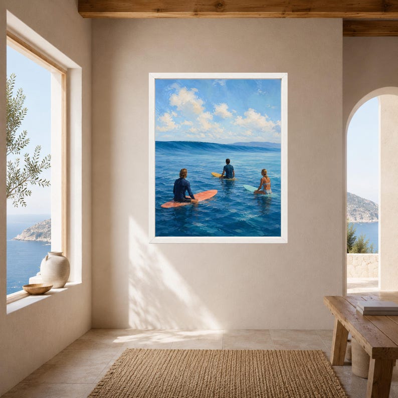 May include: A framed wall art print depicting three individuals on surfboards in the middle of a deep blue ocean. The scene features a clear sky with scattered white clouds above a calm sea, with one person on an orange board and two others.