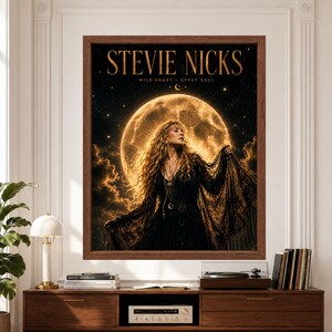 Framed Stevie Nicks wall art showing a female rock singer in flowing black lace posed before a huge glowing golden full moon, surrounded by stars against a dark celestial sky.