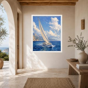 May include: A framed wall art print featuring a sailboat with a large white sail navigating deep blue ocean waters under a bright sky with fluffy white clouds, with distant rocky mountains visible on the horizon in a painterly style.