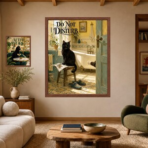 May include: Two framed wall art prints featuring black cats. The larger print shows a black cat sitting on a stool in a bathroom with the text DO NOT DISTURB. The smaller print shows a black cat sitting at a table with the text AFTER WORK.