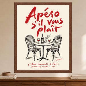 May include: A framed wall art print featuring a black and white line drawing of a bistro table with two chairs, a wine bottle, and two glasses. The text reads Ap&eacute;ro s'il vous pla&icirc;t, Libre moments &agrave; Paris, and Bistrot Chez Lucette 18h in red.