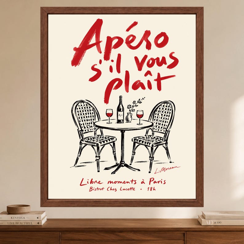 May include: A framed wall art print featuring a black and white line drawing of a bistro table with two chairs, a wine bottle, and two glasses. The text reads Ap&eacute;ro s'il vous pla&icirc;t, Libre moments &agrave; Paris, and Bistrot Chez Lucette 18h in red.