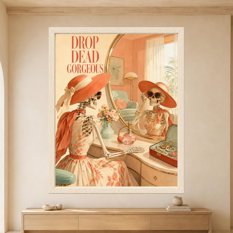 Framed Drop Dead Gorgeous skeleton wall art featuring a stylish skeleton wearing a coral sun hat and sunglasses while sitting at a retro vanity with perfume, jewelry and mirror reflection.