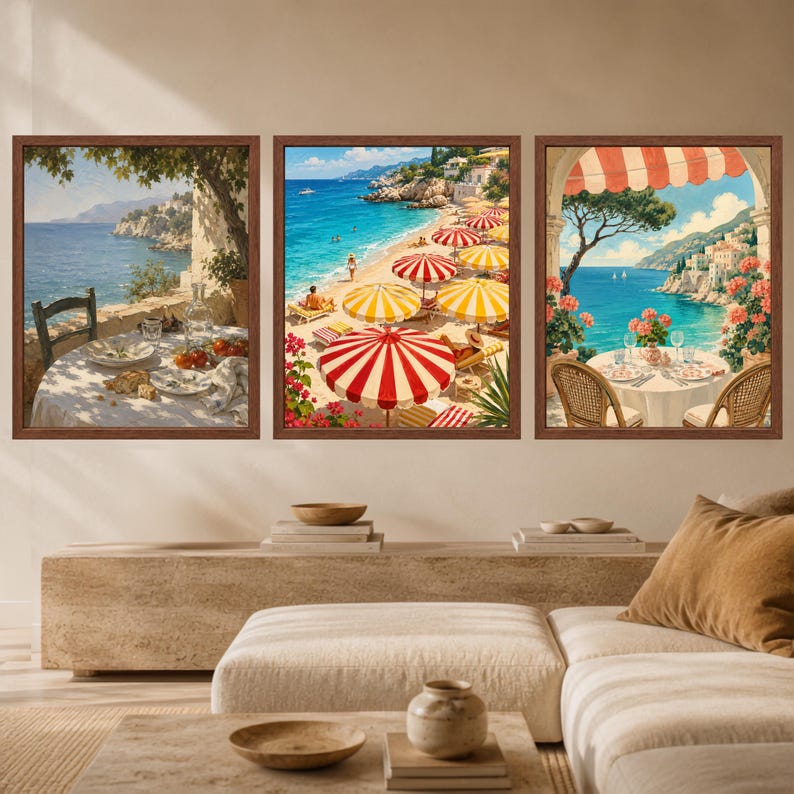 Op de afbeelding: Een set van drie ingelijste wandkunstwerken met mediterrane kusttaferelen. Links een gedekte tafel met uitzicht op zee. In het midden een zandstrand met rood-geel gestreepte parasols. Rechts een balkon met een eettafel, bloemen en een gestreepte zonwering.