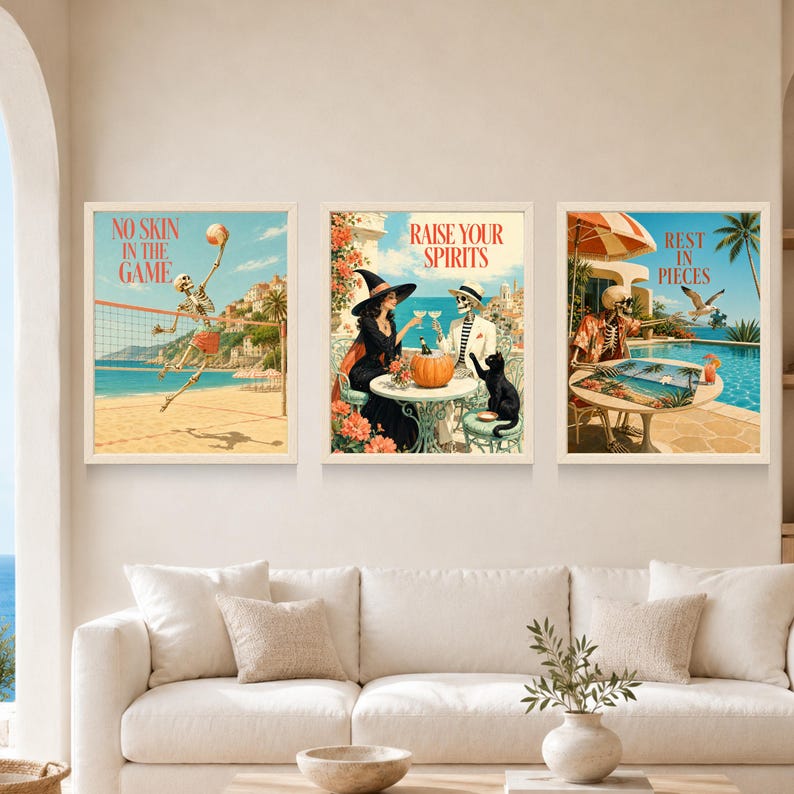 May include: Three framed wall art prints featuring skeletons in coastal settings. The left print shows a skeleton playing volleyball with the text NO SKIN IN THE GAME. The centre shows a witch and skeleton with the text RAISE YOUR SPIRITS. The right shows a skeleton with the text REST IN PIECES.