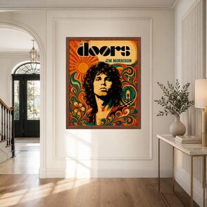 Op de afbeelding: Een rechthoekige wandkunstprint in een bruine lijst met een portret van Jim Morrison. De afbeelding bevat de tekst THE DOORS en JIM MORRISON, omringd door levendige, wervelende oranje, gele, groene en rode psychedelische patronen.