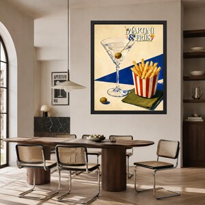 May include: A framed wall art print featuring a martini glass with an olive and a red and white striped container of french fries. The text MARTINI & FRIES is printed at the top. The background is a cream color with a bold blue diagonal stripe.