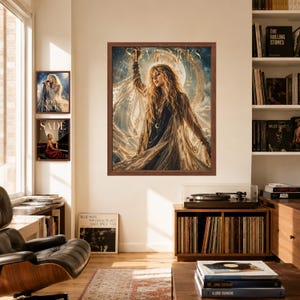 May include: A framed wall art print featuring a portrait of Stevie Nicks with long blonde hair, wearing a flowing garment against a celestial moon background. The text STEVIE NICKS is printed in gold at the top of the artwork in a dark brown frame.