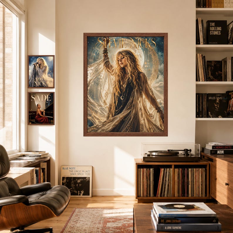May include: A framed wall art print featuring a portrait of Stevie Nicks with long blonde hair, wearing a flowing garment against a celestial moon background. The text STEVIE NICKS is printed in gold at the top of the artwork in a dark brown frame.