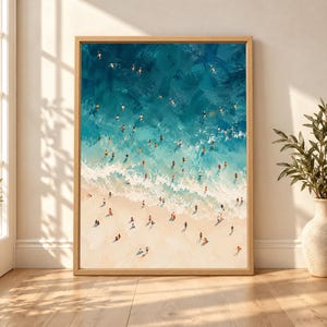 Framed aerial beach wall art showing dozens of swimmers and beachgoers in turquoise ocean water beside pale waves and a warm sandy shoreline in a textured painterly style.