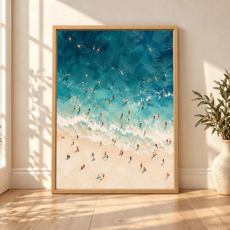 Framed aerial beach wall art showing dozens of swimmers and beachgoers in turquoise ocean water beside pale waves and a warm sandy shoreline in a textured painterly style.