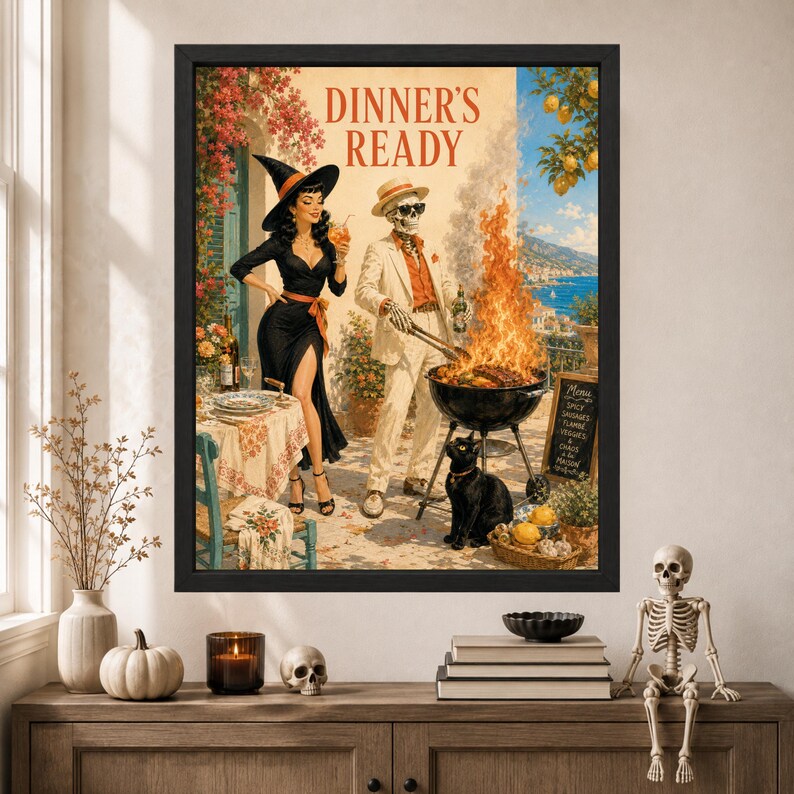 May include: A framed wall art print titled DINNER'S READY featuring a witch in a black dress and a skeleton in a white suit grilling food over an open flame. A black cat sits nearby on a patio overlooking the sea with lemon trees and flowers.