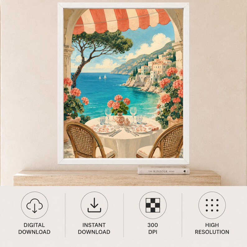 May include: A framed wall art print depicting a coastal scene viewed from a balcony with a red and white striped awning. A round table with two wicker chairs, plates, and glasses overlooks a blue sea, a rocky coastline, and white buildings.