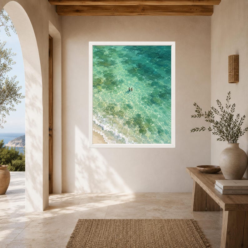 May include: A rectangular framed wall art print featuring an aerial view of a turquoise ocean with clear shallow water, a sandy shoreline with white waves, and two small figures swimming in the center of the vibrant, sunlit sea.