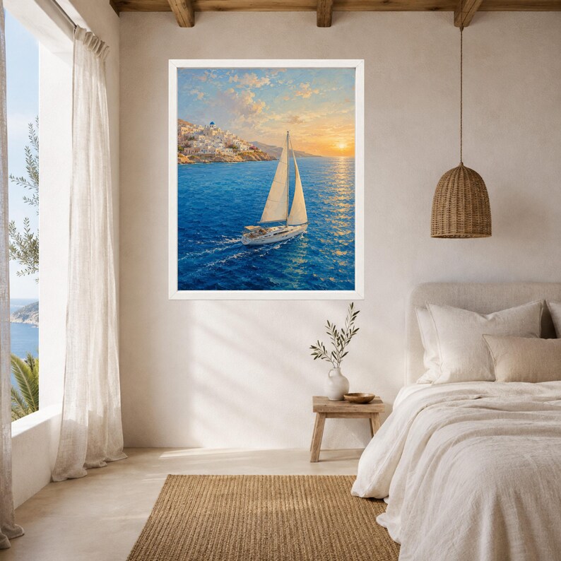 May include: A framed wall art print featuring a sailboat with white sails navigating deep blue ocean waters at sunset, with a coastal village of white buildings visible on the rocky shoreline under a soft, golden, and orange-hued sky.