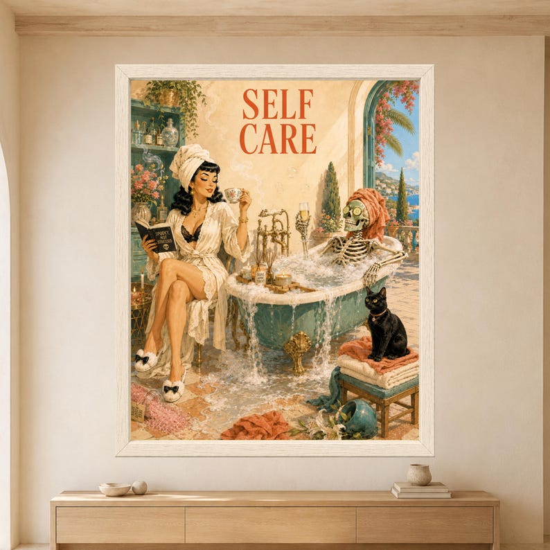 Framed Self Care wall art showing a skeleton relaxing in an overflowing turquoise clawfoot bubble bath with cucumber eyes beside a robed witch drinking tea and a black cat sitting on folded towels.