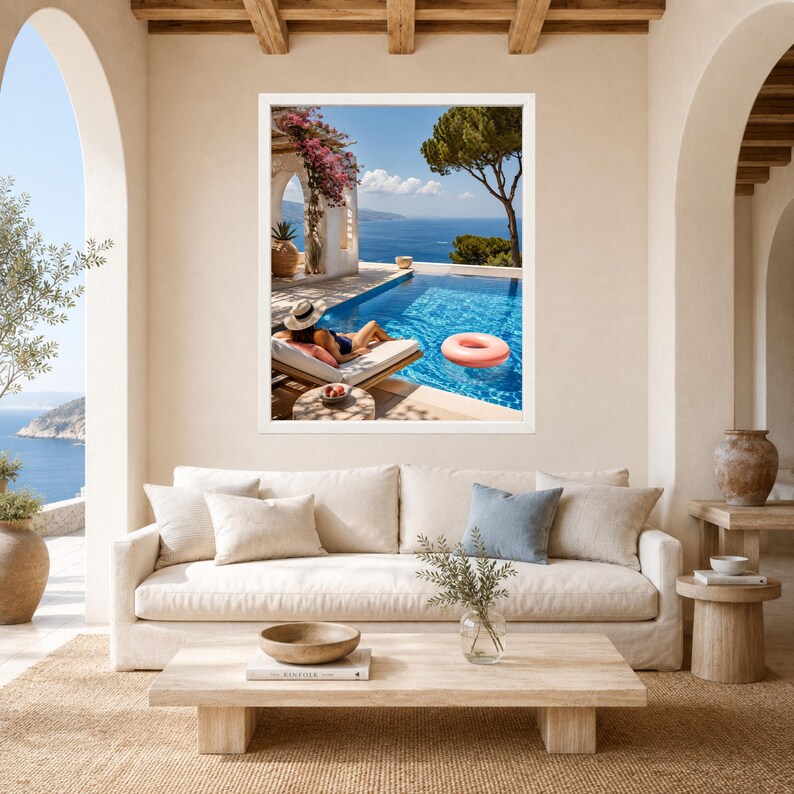 May include: A framed wall art print depicting a Mediterranean coastal scene with a swimming pool, a person in a sun hat lounging on a deck chair, a pink inflatable ring in the water, and a view of the sea under a clear blue sky.