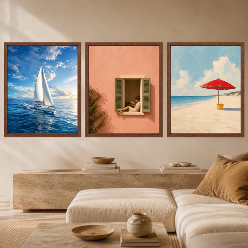 May include: A set of three framed wall art prints. The left print shows a white sailboat on blue water under a cloudy sky. The center print depicts a person sitting in an open window on a peach-colored wall. The right print features a red beach umbrella.
