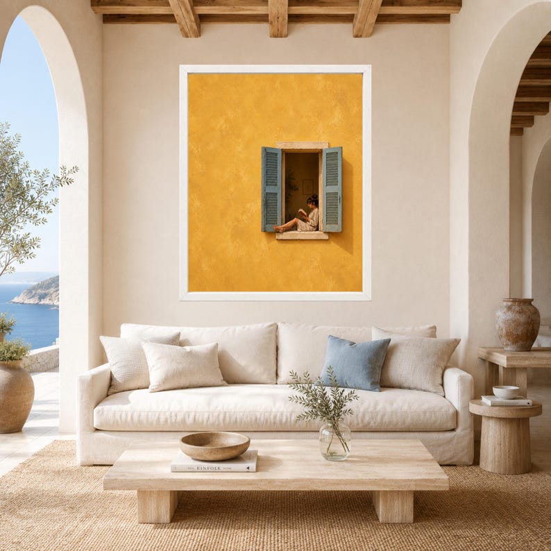 Puede incluir: Una l&aacute;mina de arte enmarcada que muestra una pared de color amarillo mostaza vibrante con una ventana abierta. La ventana tiene contraventanas de color azul claro y muestra a una persona sentada en el alf&eacute;izar leyendo un libro.